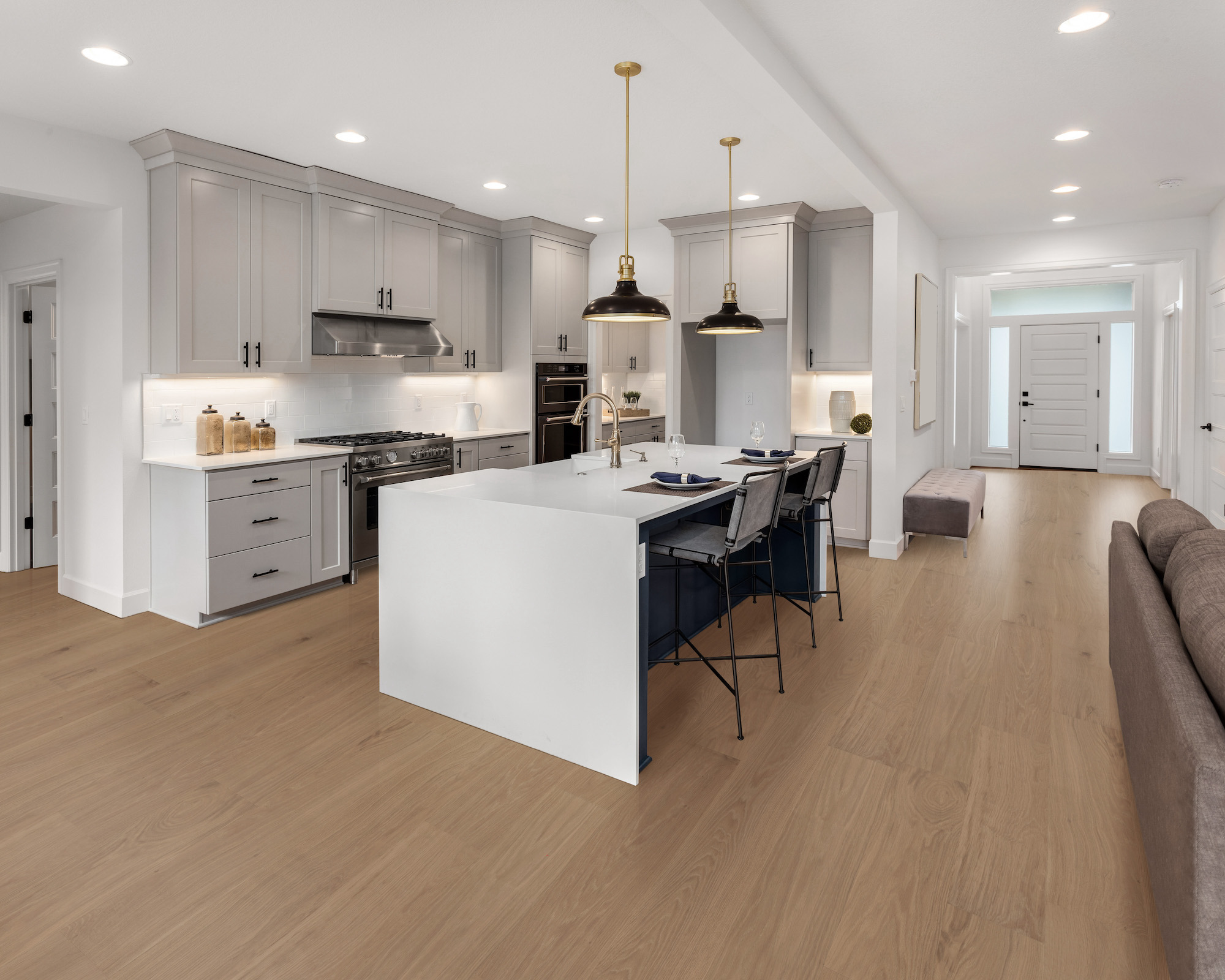 kitchen in new luxury home with waterfall island, stainless steel appliances, pendant lights, and CALI hardwood floors